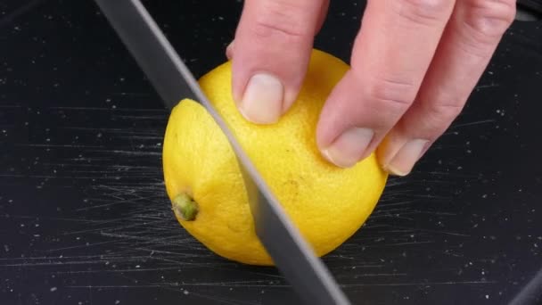 将柠檬果切割成薄片 放在黑色的切菜板上 切菜刀闭合4K — 图库视频影像