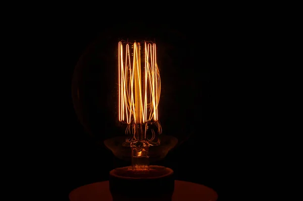 Gloeiende vintage lamp filament geïsoleerd op de donkere achtergrond — Stockfoto