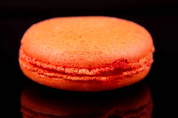 Macaron orange isolé sur le fond réfléchissant noir — Photo