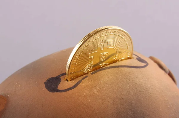 Primer plano de Bitcoin moneda simbólica insertada en la alcancía —  Fotos de Stock