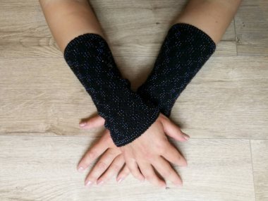 Kadın ellerinde siyah yün örgü bileklikler var.