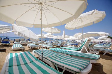 Güneşli bir günde beyaz kumaş plaj şemsiyesinin altında.