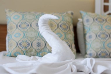 Otel yatağında beyaz banyo havlusundan yapılmış güzel bir kuğu.