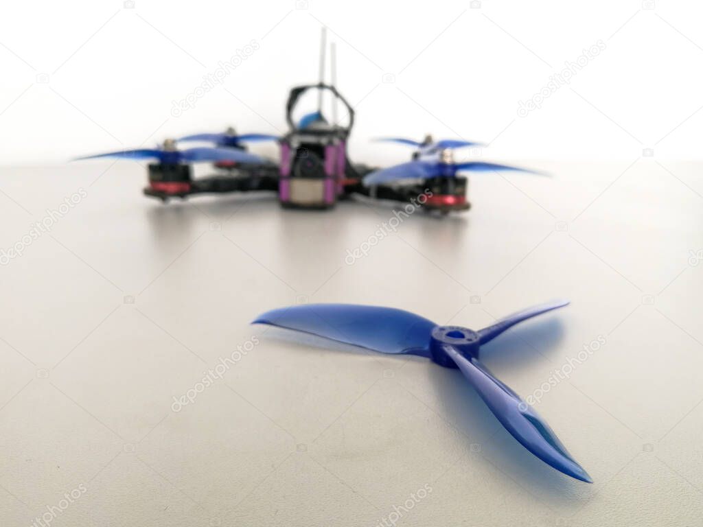 Plastic blue drone propeller in front of racing quadcopter