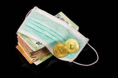 Yüz maskesinde bitcoin sembolik madeni para ve siyah arka planda izole edilmiş bir deste para. Corona Virüsü finansal kriz konsepti sırasında Bitcoin gerçek para üzerinde
