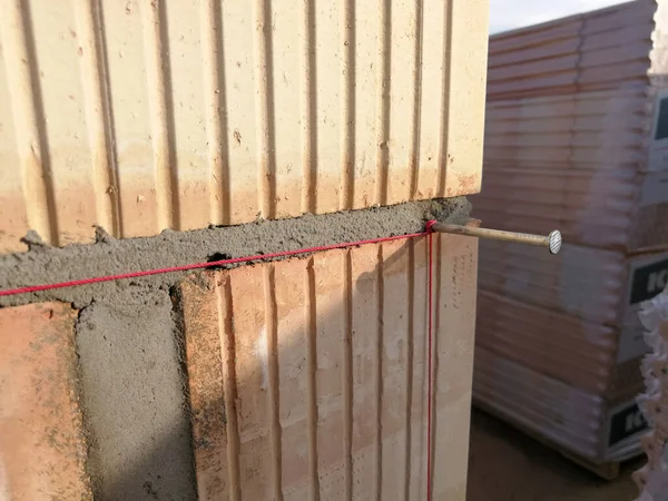 Nail and string for ceramic building block construction leveling in construction site