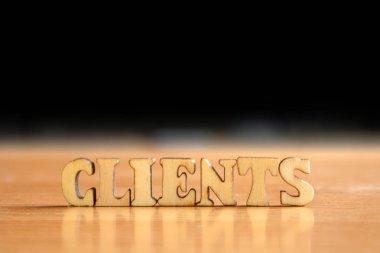 Kelime 'Müşteri' ahşap harflerin yapılmış. Tablo ve koyu siyah arka plan üzerinde ahşap yazıt