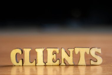 Kelime 'Müşteri' ahşap harflerin yapılmış. Tablo ve koyu siyah arka plan üzerinde ahşap yazıt