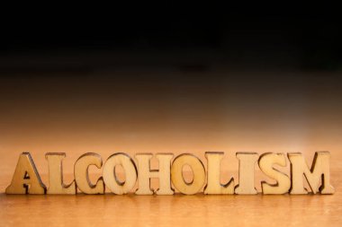 Kelime 'alkolizm' ahşap harflerin yaptı. Tablo ve koyu siyah arka plan üzerinde ahşap yazıt