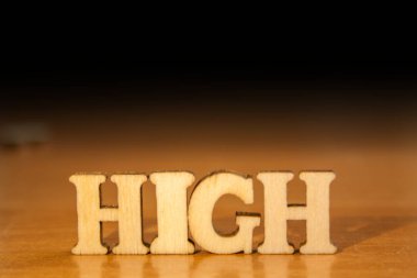 Ahşap harflerin yapılan kelime 'yüksek'. Tablo ve koyu siyah arka plan üzerinde ahşap yazıt