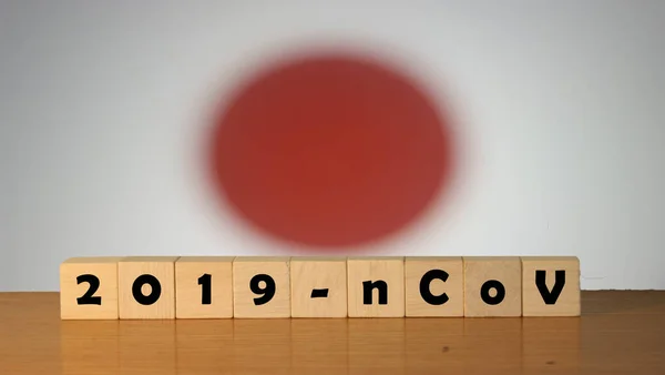 Flag of Japan with outbreak deadly coronavirus covid-19 in background. Wooden blocks with inscription 2019-nCov. Japan flag background with the spread of Coronavirus