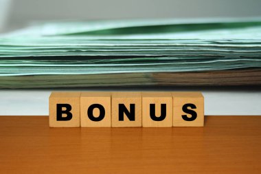 BONUS mesaj kelime ahşap bir masa üzerinde küp bloklar üzerinde bir dolar veya euro backgroun ile