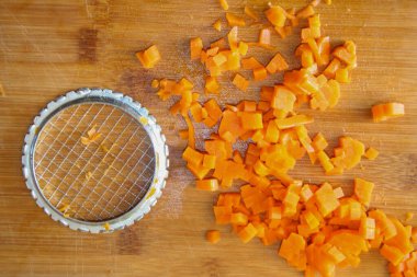 Havuç ince doğranmış. Yemek hazırlamak, sebze kesmek, sağlıklı yiyecekler. Mutfakta havuçları parçalara ayırmak. Gıda sebze portakal arka planı.