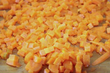 Havuç ince doğranmış. Yemek hazırlamak, sebze kesmek, sağlıklı yiyecekler. Mutfakta havuçları parçalara ayırmak. Gıda sebze portakal arka planı.