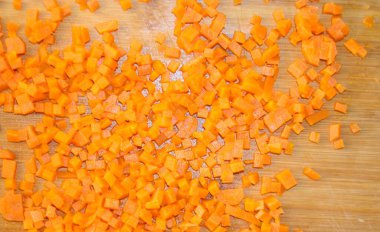 Havuç ince doğranmış. Yemek hazırlamak, sebze kesmek, sağlıklı yiyecekler. Mutfakta havuçları parçalara ayırmak. Gıda sebze portakal arka planı.