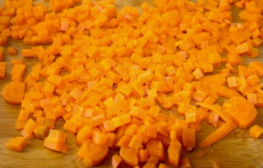 Havuç ince doğranmış. Yemek hazırlamak, sebze kesmek, sağlıklı yiyecekler. Mutfakta havuçları parçalara ayırmak. Gıda sebze portakal arka planı.
