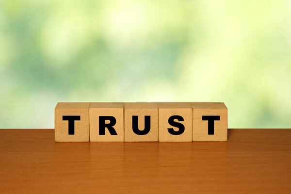 Trust message word on a wooden desk on cube blocks with a green nature backgroun