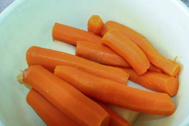 Beyaz bir kabın içinde pişmiş ve soyulmuş havuç.