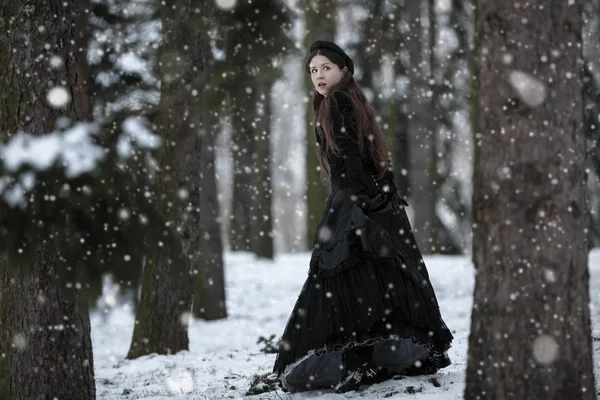 Femme en robe victorienne noire dans le parc d'hiver — Photo