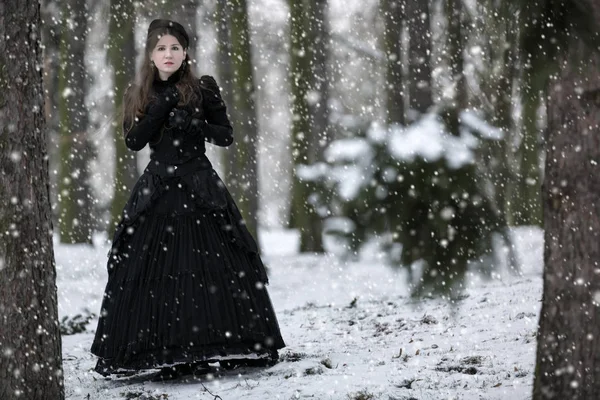 Donna in abito vittoriano nero nel parco invernale — Foto Stock