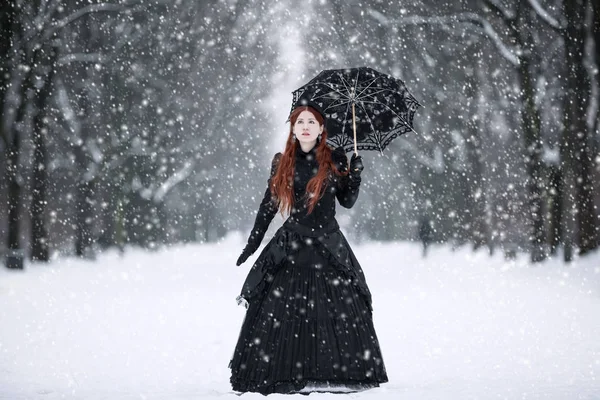 Femme en robe victorienne noire dans le parc d'hiver — Photo
