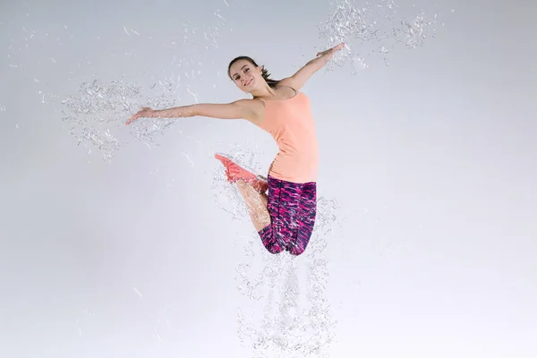 Женщина прыгает в студию и брызгает водой — стоковое фото