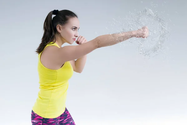 Woman striking a fist and splashing water. — Stock Photo, Image
