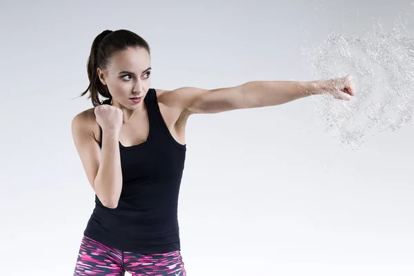 Woman striking a fist and splashing water. — Stock Photo, Image