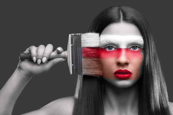 Portrait of a woman painting with a brush on her face — Stock Photo, Image