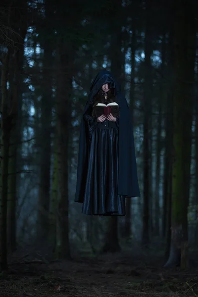 Una bruja celebrando los hechizos del libro — Foto de Stock