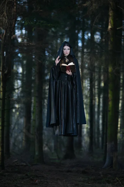 Eine Hexe, die die Zaubersprüche aus dem Buch feiert — Stockfoto