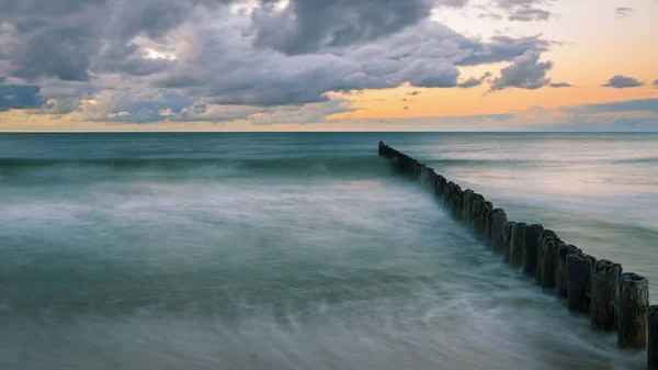 Dřevěné vlnolamu na pobřeží Baltského moře za soumraku — Stock fotografie