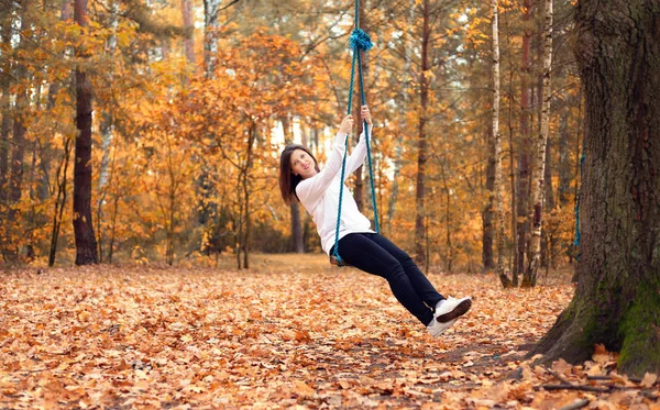 Happy woman on a swing in the autumn forest — Stock Photo, Image