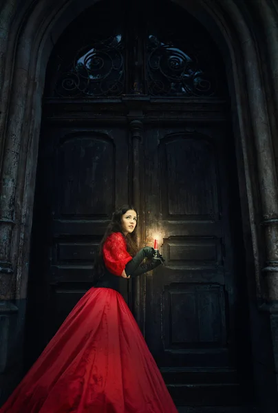 Eski kapının yanında kırmızı Viktorya dönemi elbiseli gizemli kadın. — Stok fotoğraf