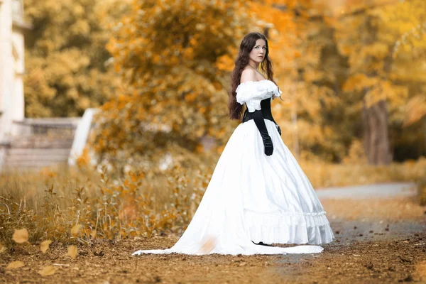 Mulher em um vestido vitoriano branco em um parque de outono — Fotografia de Stock