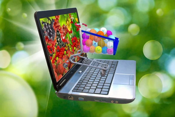 Imagen de muchas bayas en la pantalla de un ordenador portátil, vitaminas estilizadas en el carrito de comida —  Fotos de Stock