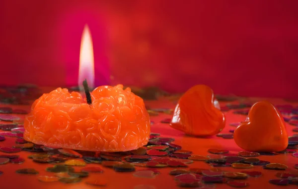 Vela ardiente y corazones decorativos sobre un fondo rojo —  Fotos de Stock