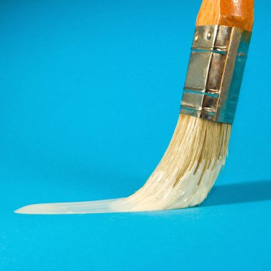 image of brush and white paint on a blue background close-up clipart