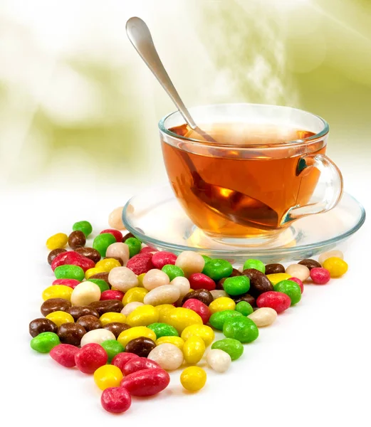 Чашка з чаєм і цукерками на розмитому фоні — стокове фото