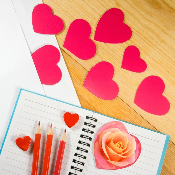 Obálka, růžový květ, tužky a stylizované srdce — Stock fotografie
