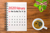kalendář obrázek pro únor 2020.Káva, květiny a barevné kousky papíru na deskách