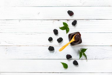 Beyaz Ahşap Arkaplan 'da bir kavanoz Blackberry reçeli. Seçici odak.