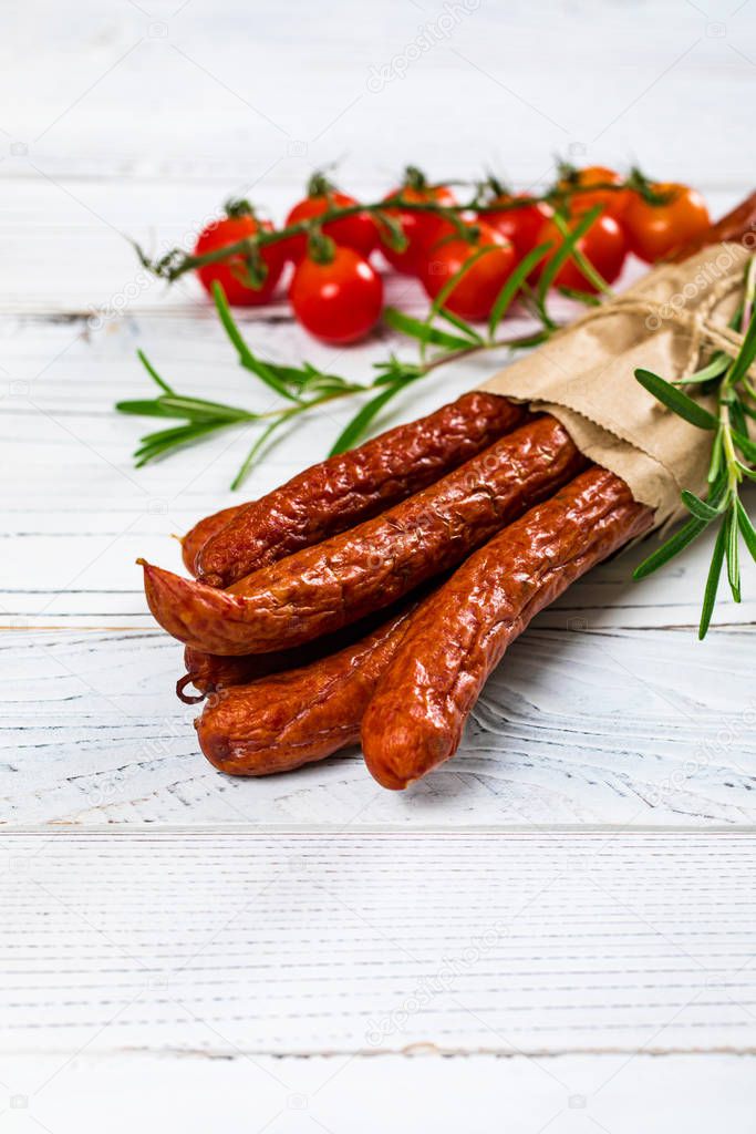 Kabanos or Cabanossi Thin Dry Smoked Polish Sausage on White Wooden Background. Selective focus.