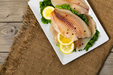 Ahşap arka planda Whitefish Tilapia balık RAW fileto. Seçici odak.