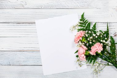Eski Ahşap Arkaplan 'daki karanfil çiçeklerinin kağıt yaprağıyla üst görüntüsü. Anneler günü için tasarım konsepti, düğün ve fotokopi odalı sevgililer günü. Seçici odak.