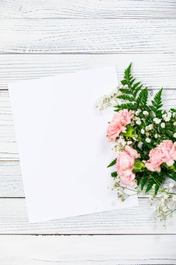 Eski Ahşap Arkaplan 'daki karanfil çiçeklerinin kağıt yaprağıyla üst görüntüsü. Anneler günü için tasarım konsepti, düğün ve fotokopi odalı sevgililer günü. Seçici odak.