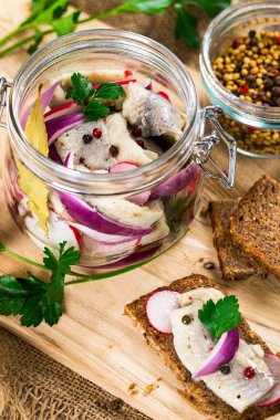 Baharatlı, turplu ve ahşap arka planda kırmızı soğanlı marine edilmiş ringa balığı. Seçici odak.