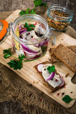 Baharatlı, turplu ve ahşap arka planda kırmızı soğanlı marine edilmiş ringa balığı. Seçici odak.