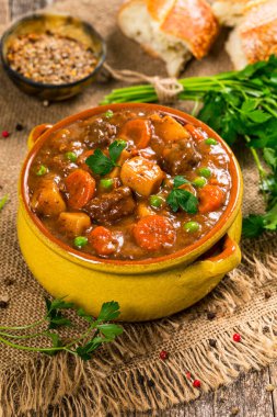 Tahta arka planda patates ve havuçlu biftek güveci. Seçici odak.