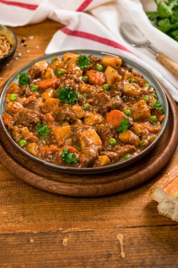 Tahta arka planda patates ve havuçlu körili biftek. Seçici odak.